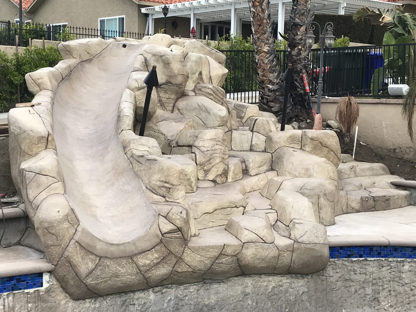 Custom rock waterslide built into a backyard pool