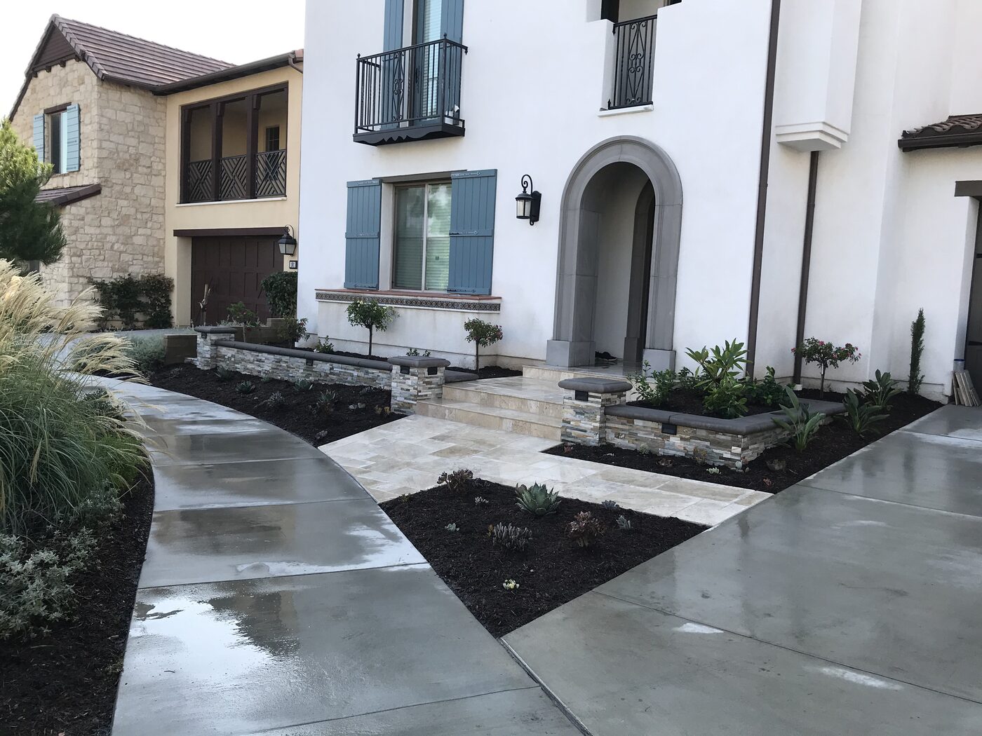 Front yard landscaping with stone planter walls, travertine walkway and new plantings