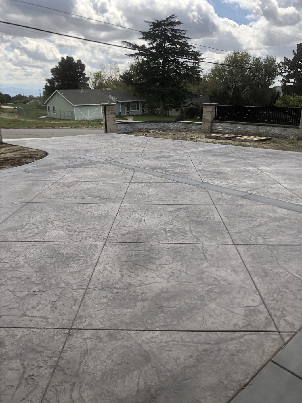 Large stamped concrete driveway approach to a hillside home
